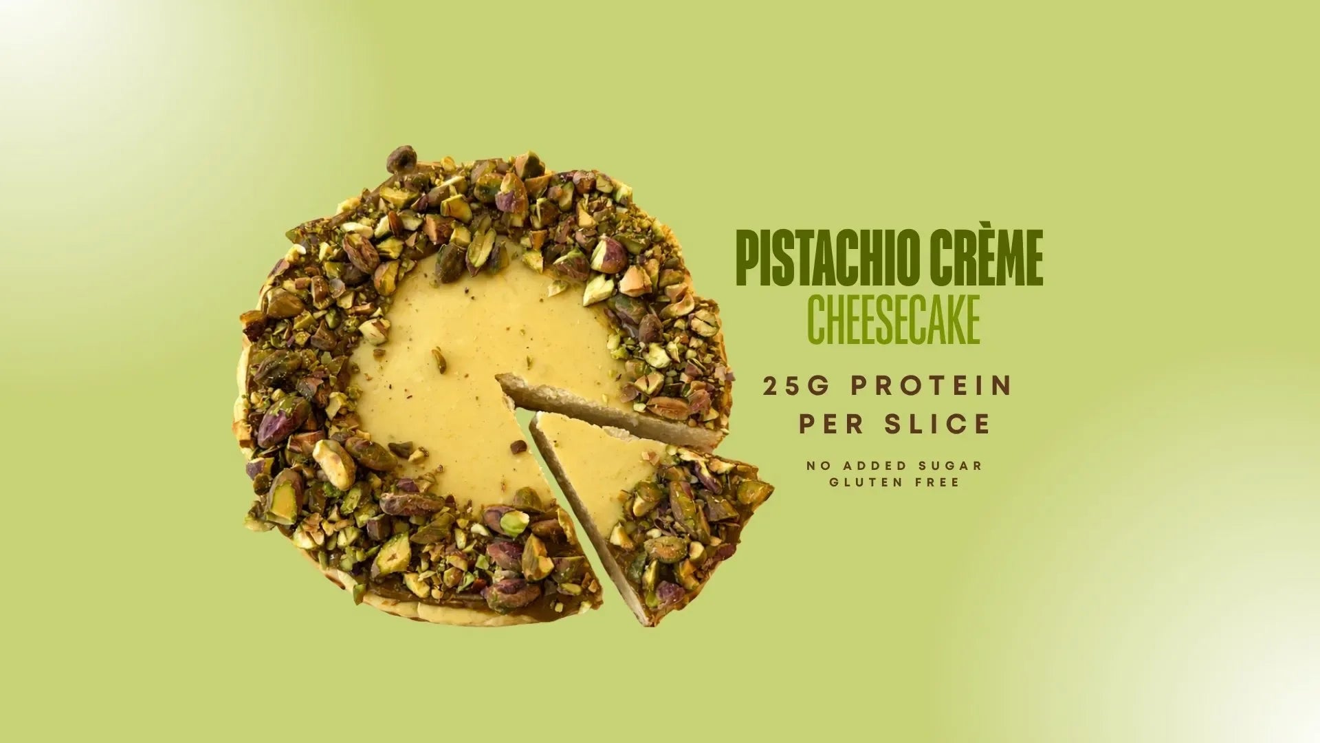 A pistachio crème cheesecake shown as a round slice with a wedge cut out, on a light green gradient background. Text on the right reads 'PISTACHIO CRÈME CHEESECAKE', '25G PROTEIN PER SLICE', and 'NO ADDED SUGAR GLUTEN FREE'.