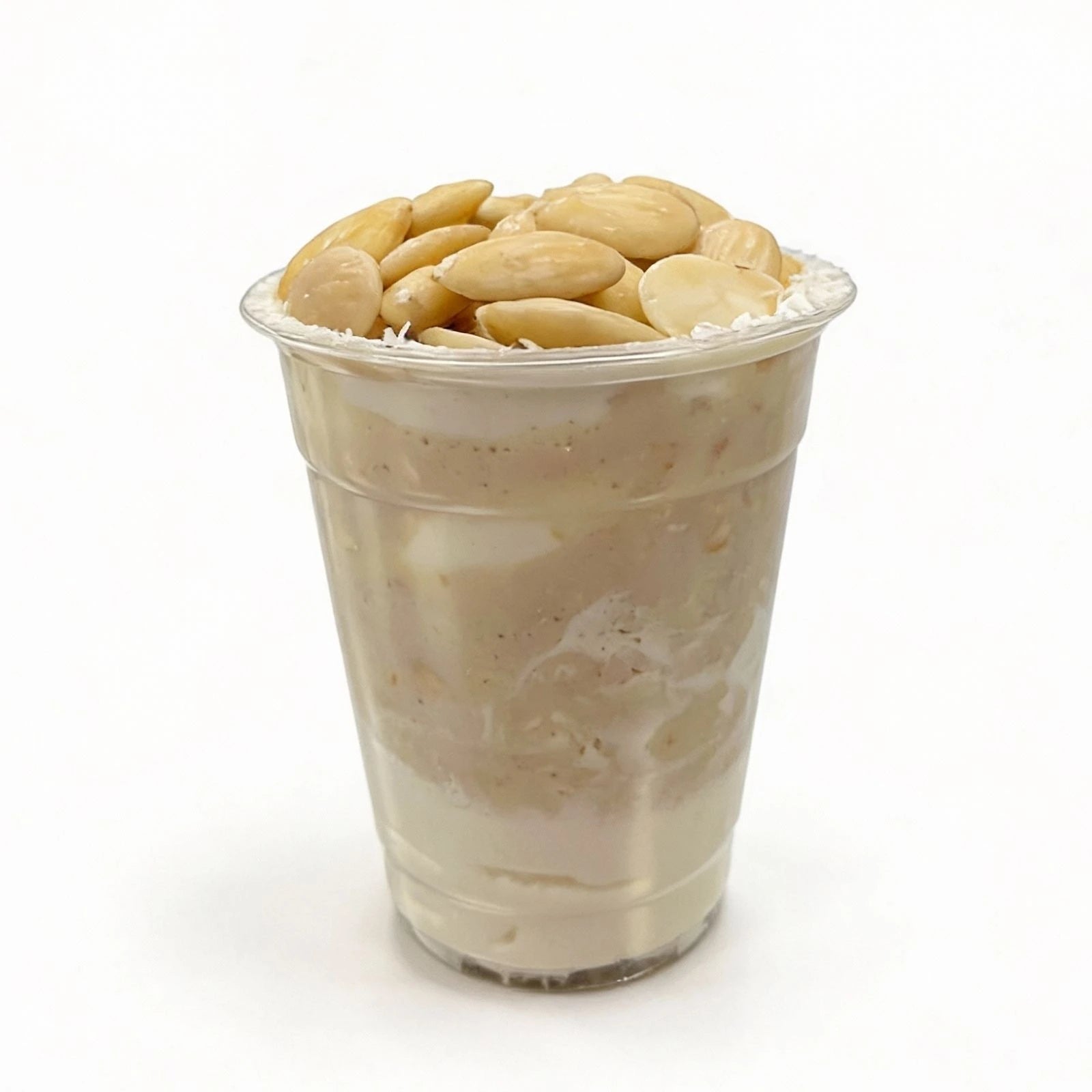 Clear plastic cup filled with a creamy dessert topped with almonds on a white background