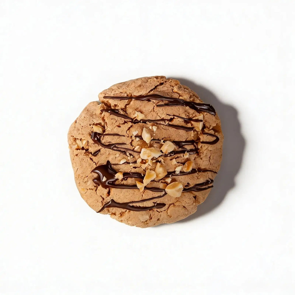 Protein cookie with chocolate drizzle and nuts on a white background